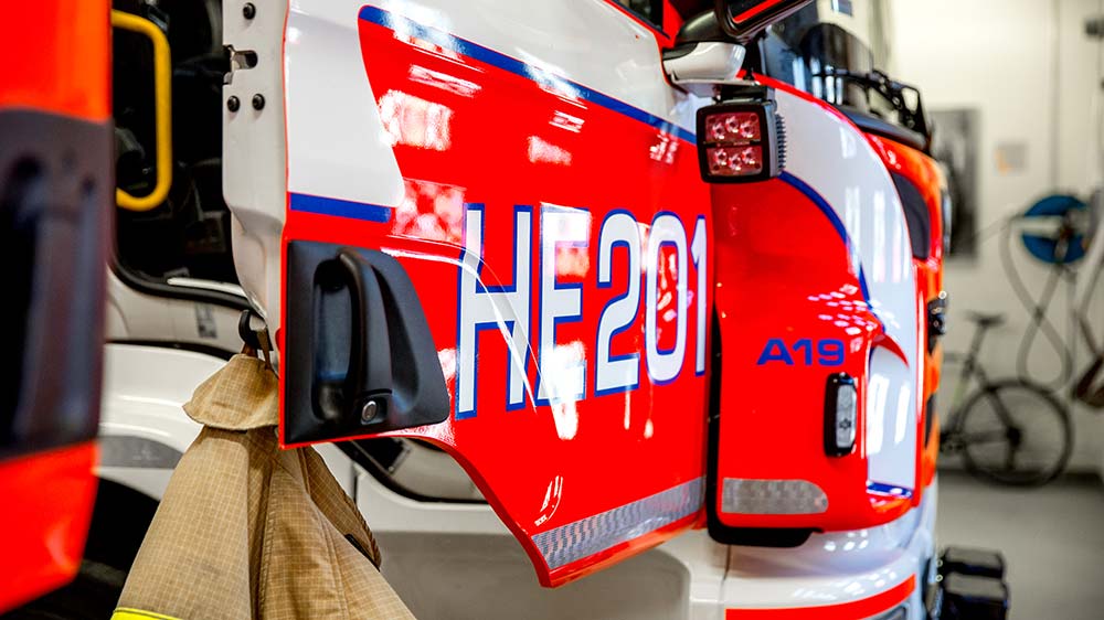 Paloauto, jonka ovessa lukee tunnus HE201. Paloauton ovesta roikkuu pelastajan takki.