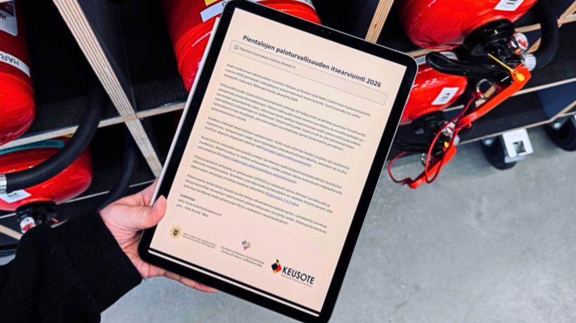 Henkilöllä on kädessään tabletti, jonka näytöllä on 