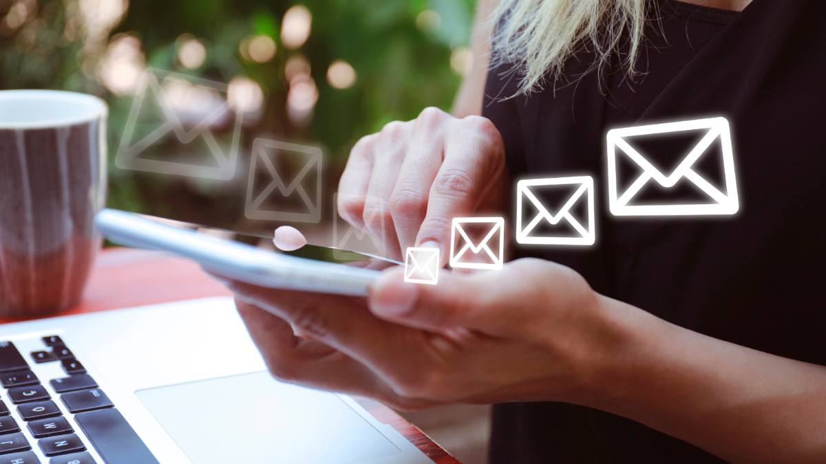 Kännykkä kädessä ja sähköpostikuvakkeita