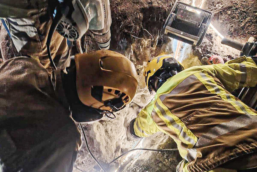 Kaksi pelastajaa katsovat kallioiden väliin.