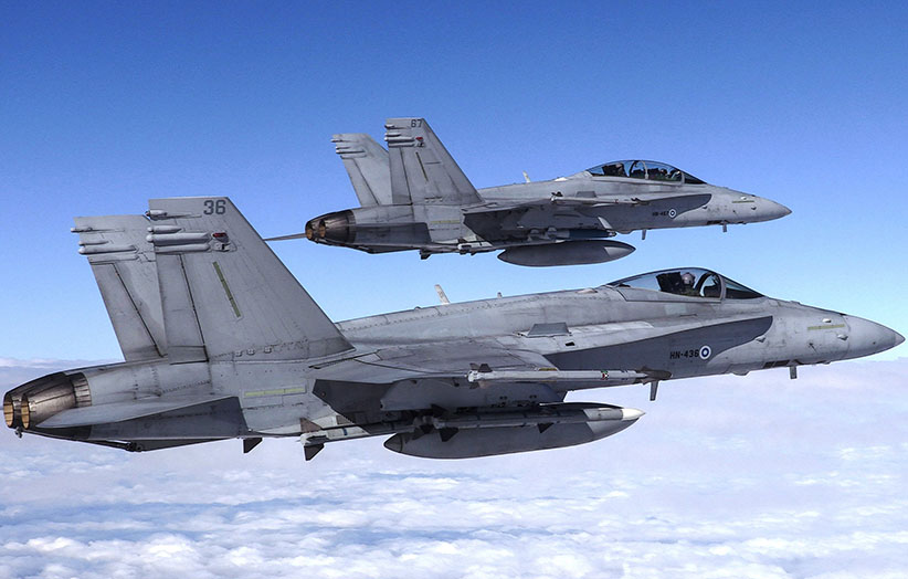 Kaksi Hornet-hävittäjää lentää vierekkäin pilvien yläpuolella. Kuva on Ilmavoimien ottama.