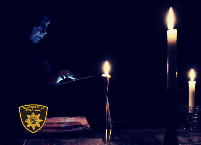 Nainen selailee tablettia kolmen kynttilän valossa.