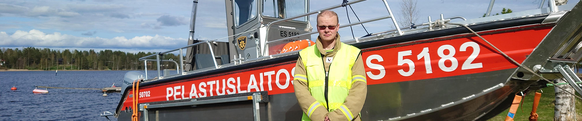 Rantasalmen sopimuspalokunnan Marko Julkunen seisoo pelastusveneen vieressä järven rannalla.