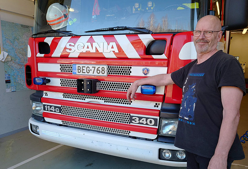 Rauno Pesonen nojailee paloauton keulaan ja katsoo hymyillen kameraan.