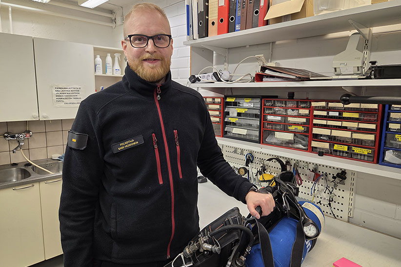 Pelastaja Sami Heikkinen asema-asussa. Viereisellä pöydällä on paineilmalaite.