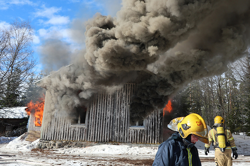 Kuvituskuva palavasta talosta. Etualalla näkyy myös Etelä-Savon pelastuslaitoksen henkilöstöä, joka harjoitteli talon sammutusta.