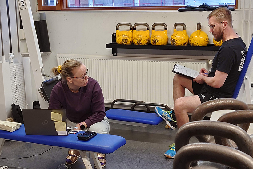 Työhyvinvointikoordinaattori Tiia Kokkonen keskustelee kuntotestin juuri suorittaneen pelastajan kanssa testin tuloksista paloaseman kuntosalilla.