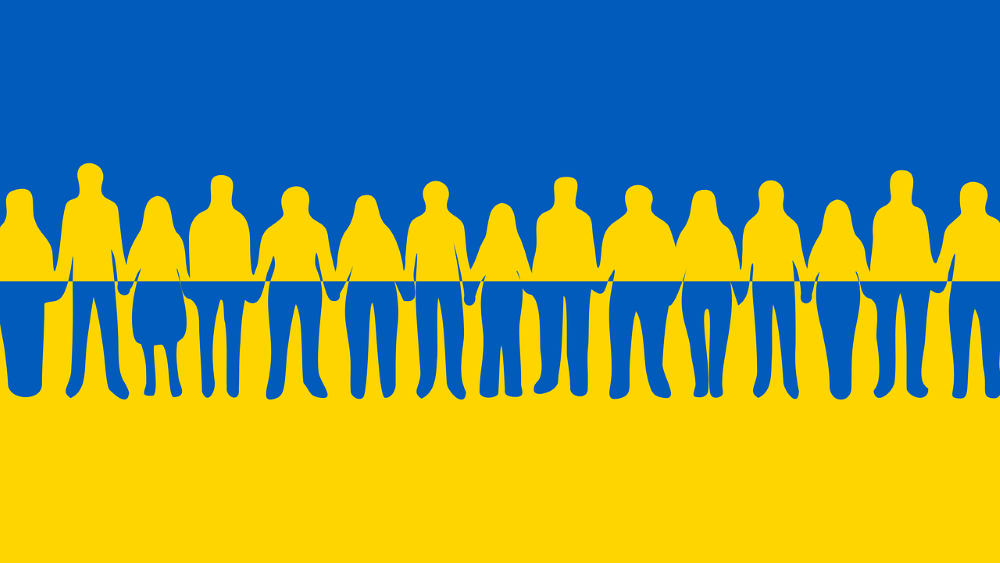 Piirroskuva: Ukrainan lippu ja ihmisiä käsi kädessä