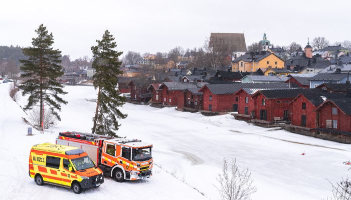 Ambulanssi ja paloauto Porvoonjoen rannalle pysäköitynä. Takana avautuu näkymä Vanhaan Porvooseen.