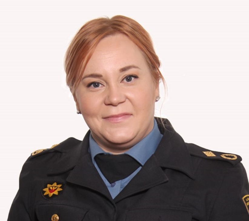 Pelastusalan siniseen virka-asuun pukeutunut nainen kasvokuvassa.