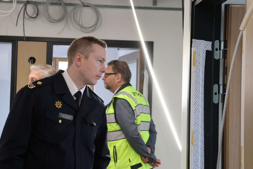 Pelastuspäällikkö ja keltaiseen liiviin pukeutunut rakennustyöntekijä Karhulan paloaseman rakennusvaiheessa olevissa konttoritiloissa.