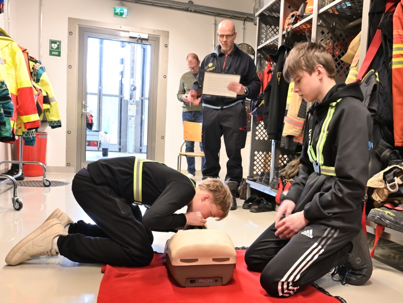 Nuoria harjoittelemassa elvytystä, yksi puhaltaa nuken suuhun.