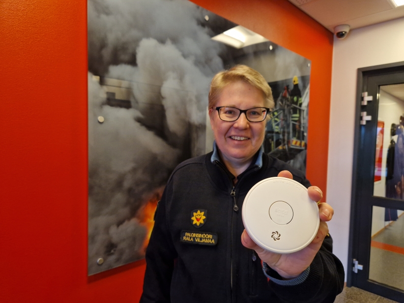 Pelastusalan virka-asuun pukeutunut henkilö palovaroitin kädessä.