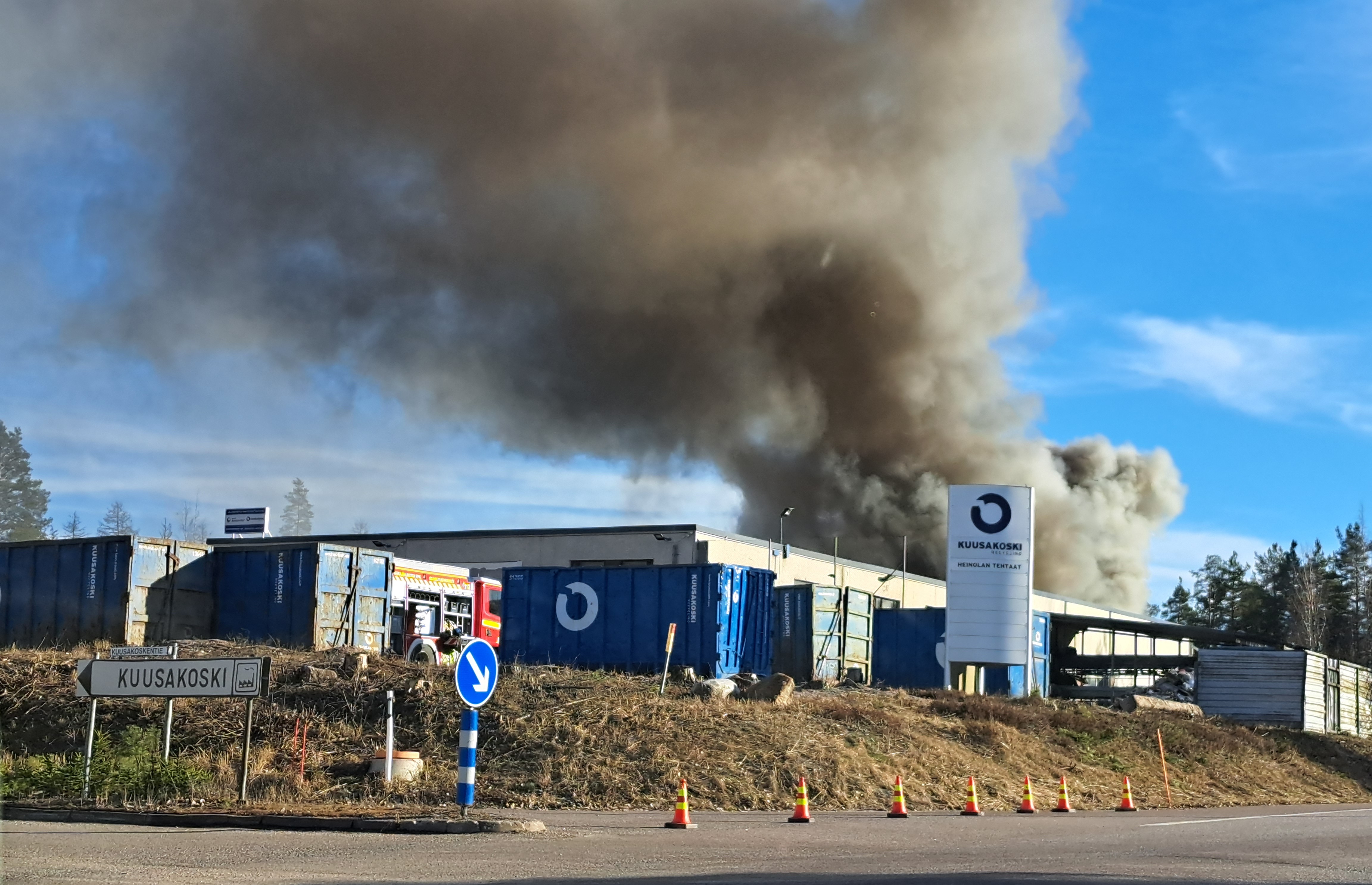 Savuava tehdasrakennus, kyltissä teksti Kuusakoski.