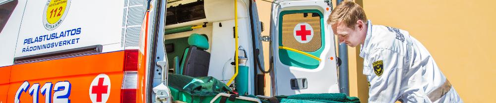 Sairaankuljettaja laittaa paareja ambulanssiin.