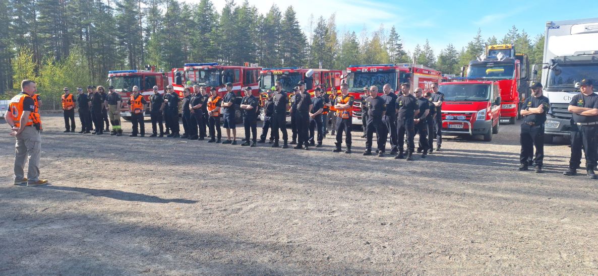 Maastopalomuodostelman harjoitukseen osallistuvia palomiehiä ja taustalla paloautoja.