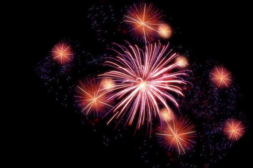 Mustalla pohjalla värikkäitä ilotulitteita.