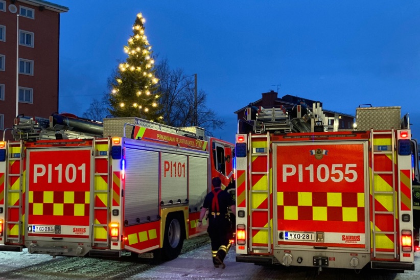 Paloautot lähdössä hälytykselle Tampereen Keskuspaloaseman pihasta. Taustalla valaistu joulukuusi.