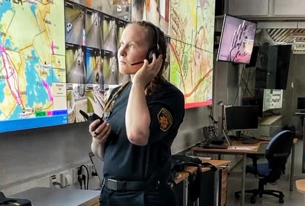 Palomestari kuuntelee radiopuhelinta karttataulujen edessä pelastuslaitoksen tilanne- ja johtokeskuksessa.