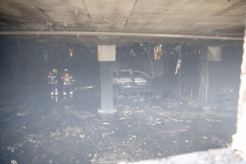 Palomiehiä sammutusvarusteissaan palaneessa parkkihallissa.