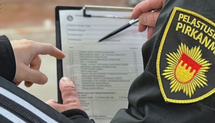  Pelastuslaitoksen kahden työntekijän kädet. Toisella kädessä lomake, jota tarkastelevat yhdessä. 