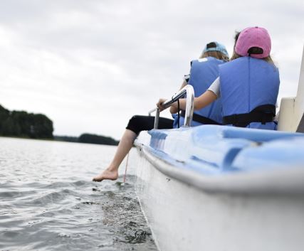 Kaksi lasta veneen kyydissä pelastusliivit päällään.