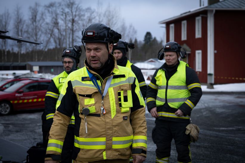 Neljä pelastajaa ja taustalla rakennus.