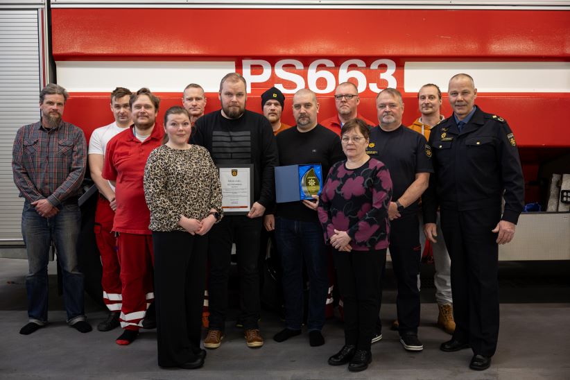 Pelastuslaitoksen henkilöstöä yhdessä elämän liekki -palkinnon saaneen auttajan kanssa paloauton edessä.