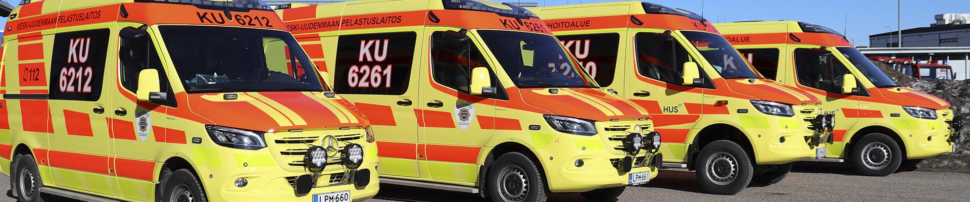 Neljä uutta ambulanssia vierekkäin paloaseman pihalla.