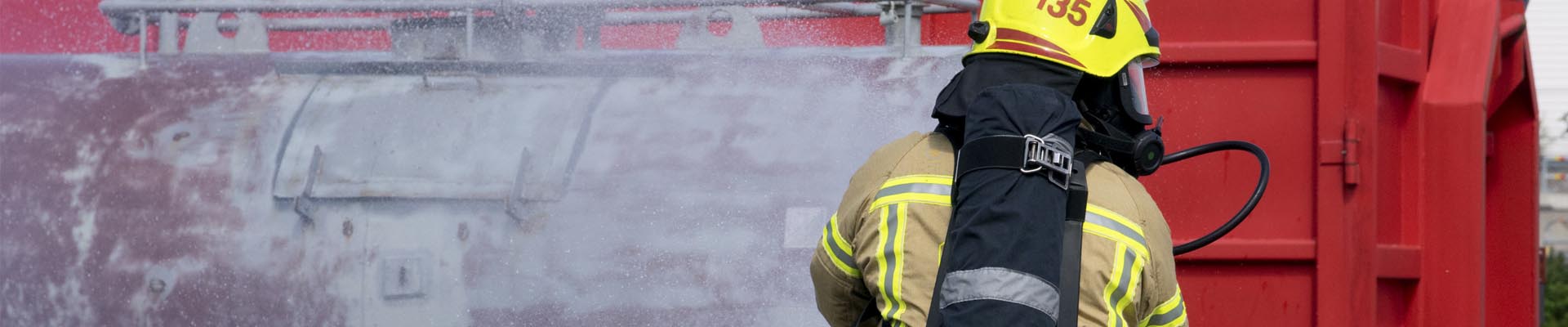 Palomies sammuttaa kemikaalisäiliötä sammutusletkulla toimintaharjoituksessa.