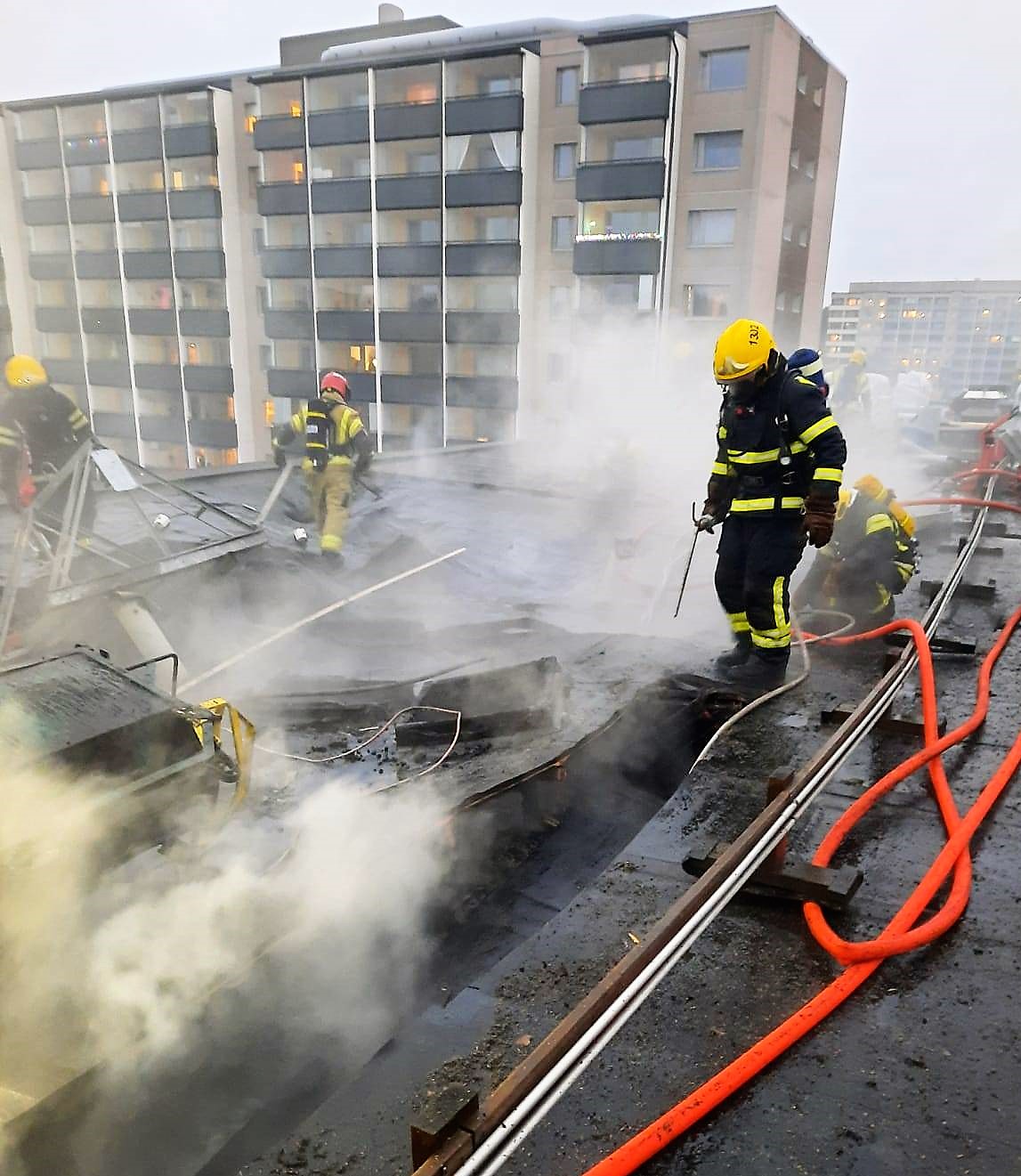 Brandmän släcker en eldsvåda på ett höghustak.