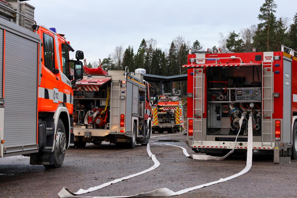 Fire trucks parked on a field of sand.