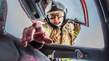  En brandman sträcker handen in från bilrutan 